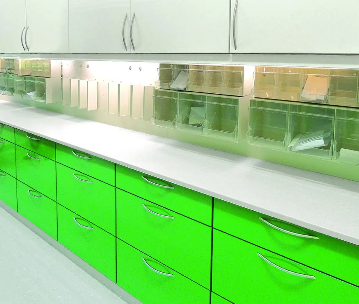 Möbelzeile mit leuchtend grünen Schubladen und Glas-Oberschränken